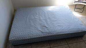 A mattress with a textured surface, placed on a tiled floor. - Hospedagem  (Sao Gabriel)