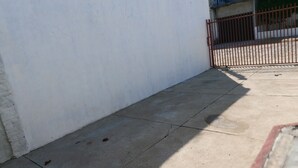 A corner of a building with a concrete floor and a metal gate. - Hospedagem  (Sao Gabriel)