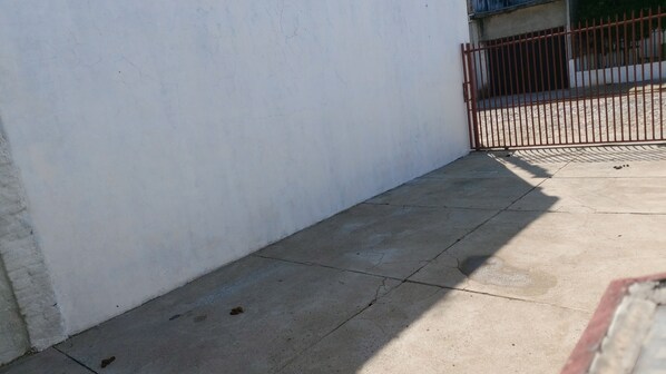 A corner of a building with a concrete floor and a metal gate. - Hospedagem  (Sao Gabriel)