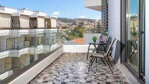 A balcony with a tiled floor, a glass railing, and a table with chairs.