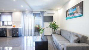 A modern living room with a grey sofa, a black coffee table, and a painting on the wall.