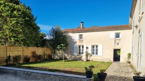 A house with a tiled roof, a stone pathway, and a small garden with potted plants. - Le gite d'URYA - Ideal for a romantic vacation (Saint-Mard)