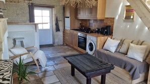 A cozy living room with a sofa, a coffee table, and a dining area. - Le gite d'URYA - Ideal for a romantic vacation (Saint-Mard)