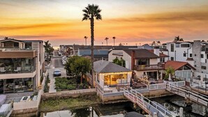 A residential area with modern houses, a small dock, and a sunset sky.