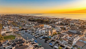 A coastal town with a marina, residential buildings, and a sunset over the ocean.