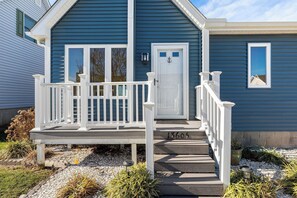 A blue house with a white front porch and steps leading to the door.