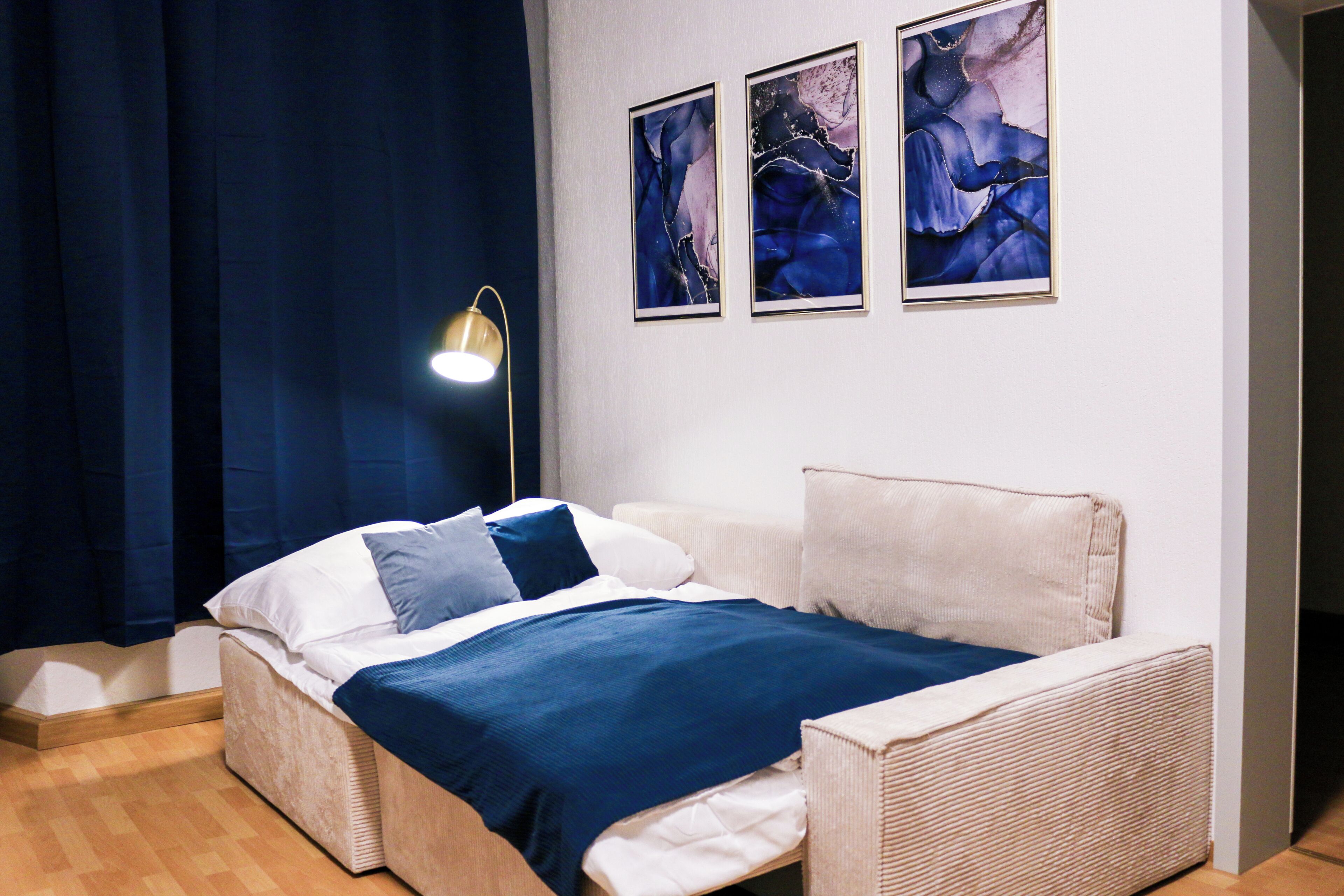 Een slaapkamer met een bed, een bedlampje en drie ingelijste kunstwerken aan de muur.