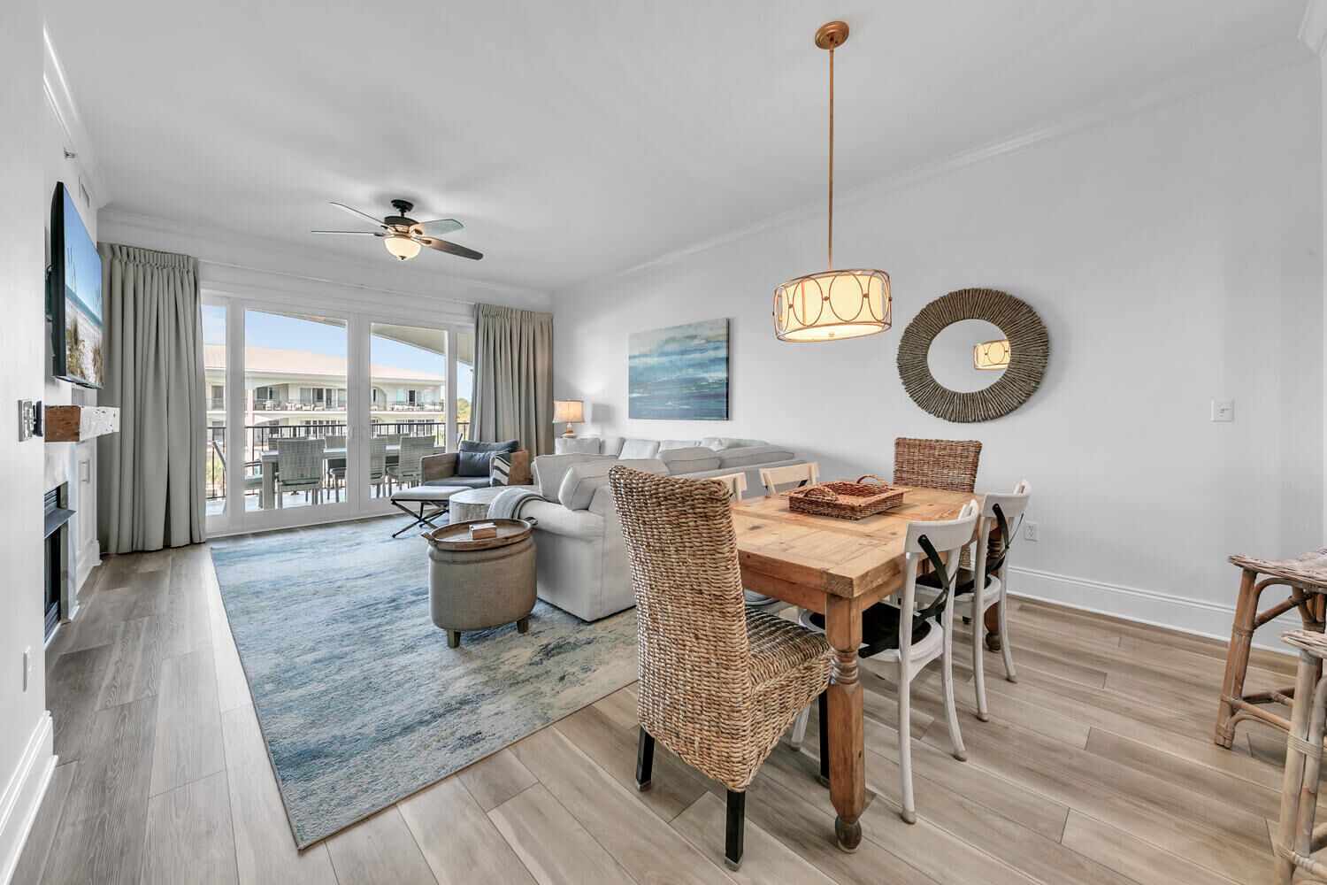 Een ruime woonkamer met een eettafel, rieten stoelen en een plafondventilator.