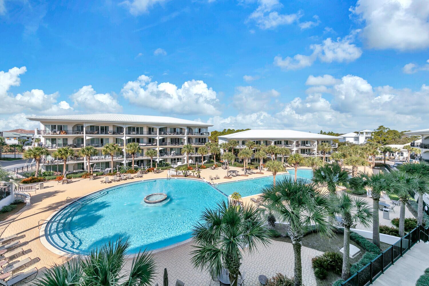 Ein Resort mit großem Pool, mehreren Balkonen und Palmen.