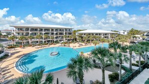 Een resort met een groot zwembad, meerdere balkons en palmbomen.