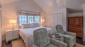 A bedroom with a large bed, two nightstands, a wooden cabinet, patterned armchairs, and a chandelier. - Steps to Vanderbilt Beach, Sleeps 13, Resort-Style Backyard (Naples)
