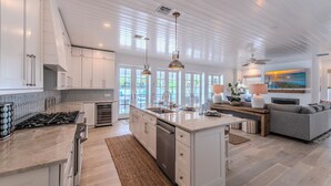 A spacious kitchen with a central island, built-in appliances, and a large window offering a view of the outdoors. - Steps to Vanderbilt Beach, Sleeps 13, Resort-Style Backyard (Naples)