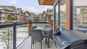 Un balcon agrémenté de chaises et d’une table en osier, d’où l’on peut admirer une rangée de maisons de ville aux couleurs vives.
