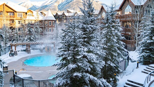 A resort with a pool, snow-covered trees, and mountain views. - Mountain View Stoneridge - Pool & Hot Tub & Sauna (Canmore)