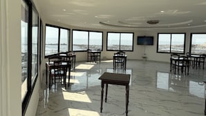 A spacious room with large windows offering ocean views, a flat-screen TV mounted on the wall, and a polished marble floor. - Setifana Sea view  (Conakry)