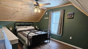 Ein Schlafzimmer mit Bett, Schreibtisch und einem Fenster mit Vorhängen.