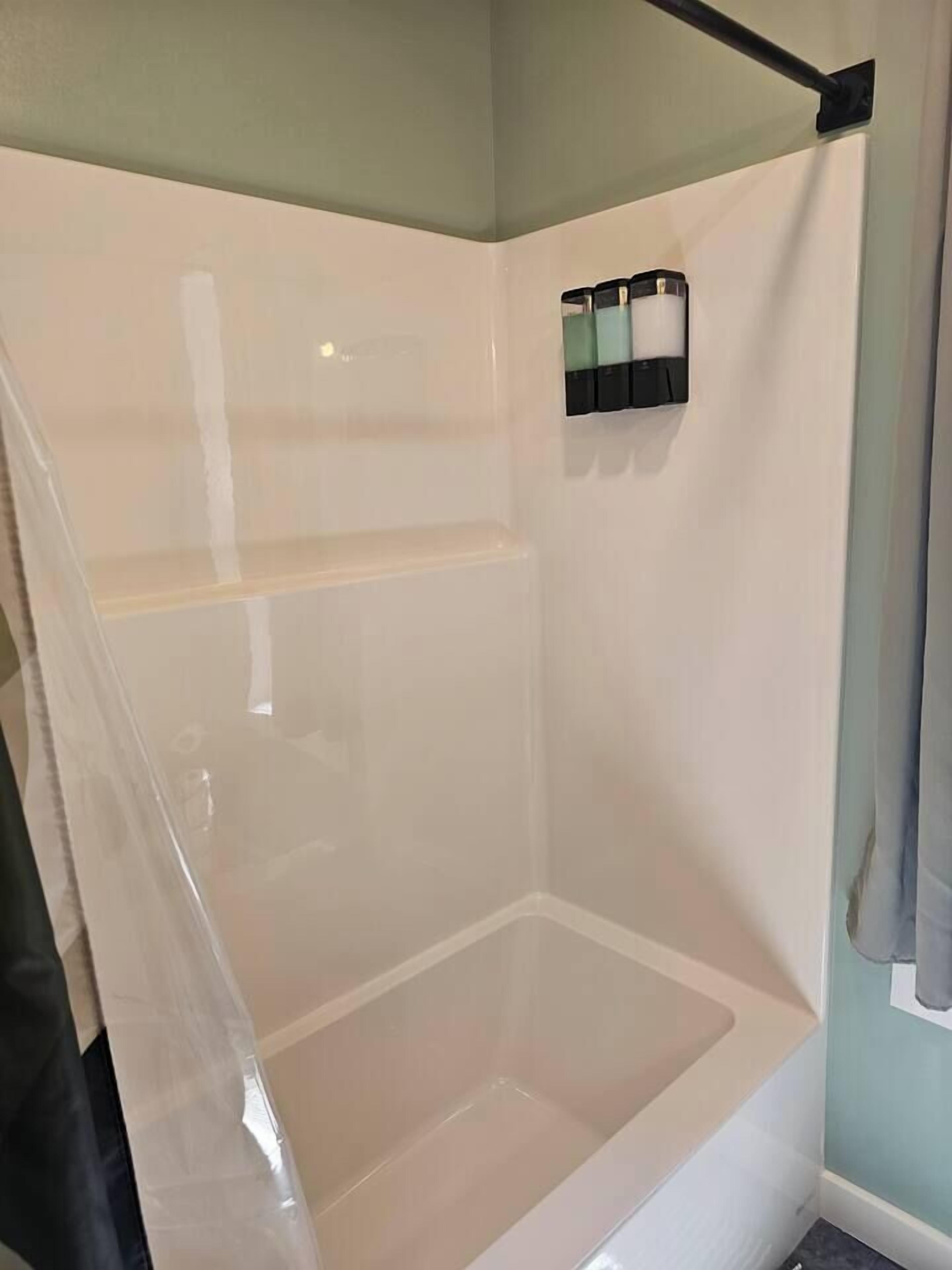 Een badkamer met een witte badkuip, een douchegedeelte en een handdoekrek met toiletartikelen.