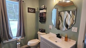 Ein Badezimmer mit Holzboden, einem großen Spiegel, einem Waschbecken und einer Toilette.