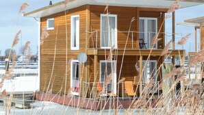 Une cabane en bois dotée d’un balcon, de fenêtres et d’une antenne parabolique.