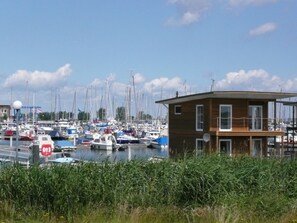 Een jachthaven met verschillende boten afgemeerd, een klein houten gebouw en een heldere lucht.