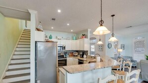 A spacious kitchen with a central island, white cabinetry, and a stainless steel refrigerator.