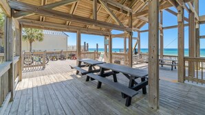 A wooden deck with picnic tables and a view of the ocean.