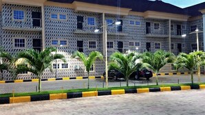 A multi-story building with a patterned facade, a paved parking area, and palm trees. - Rotana Hotel  (Ilorin)