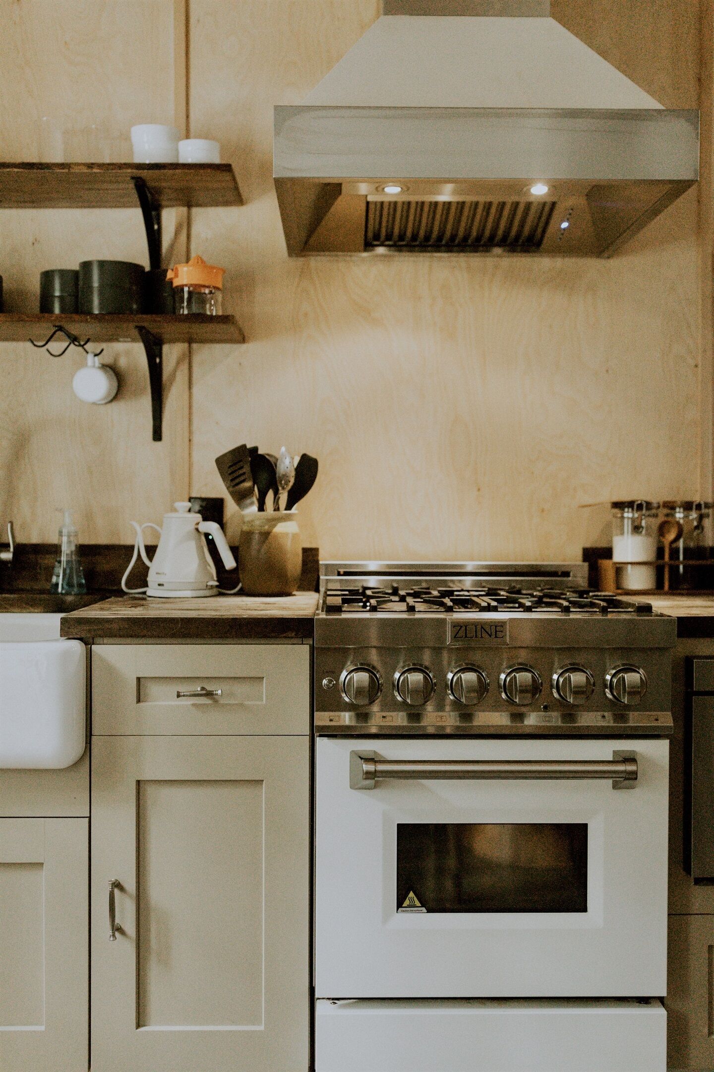 Une cuisine équipée d’une cuisinière, d’un four et de divers ustensiles de cuisine posés sur le plan de travail.