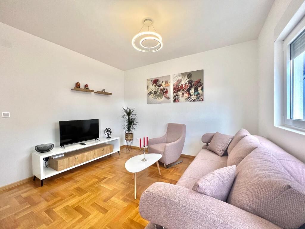 Una sala de estar moderna con un sofá, televisor y objetos decorativos.
