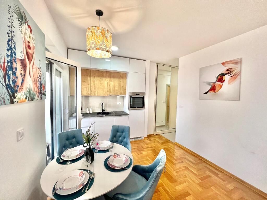 Un espace repas moderne avec une table ronde pour quatre personnes, une chaise rembourrée de couleur bleue et un luminaire suspendu au-dessus.