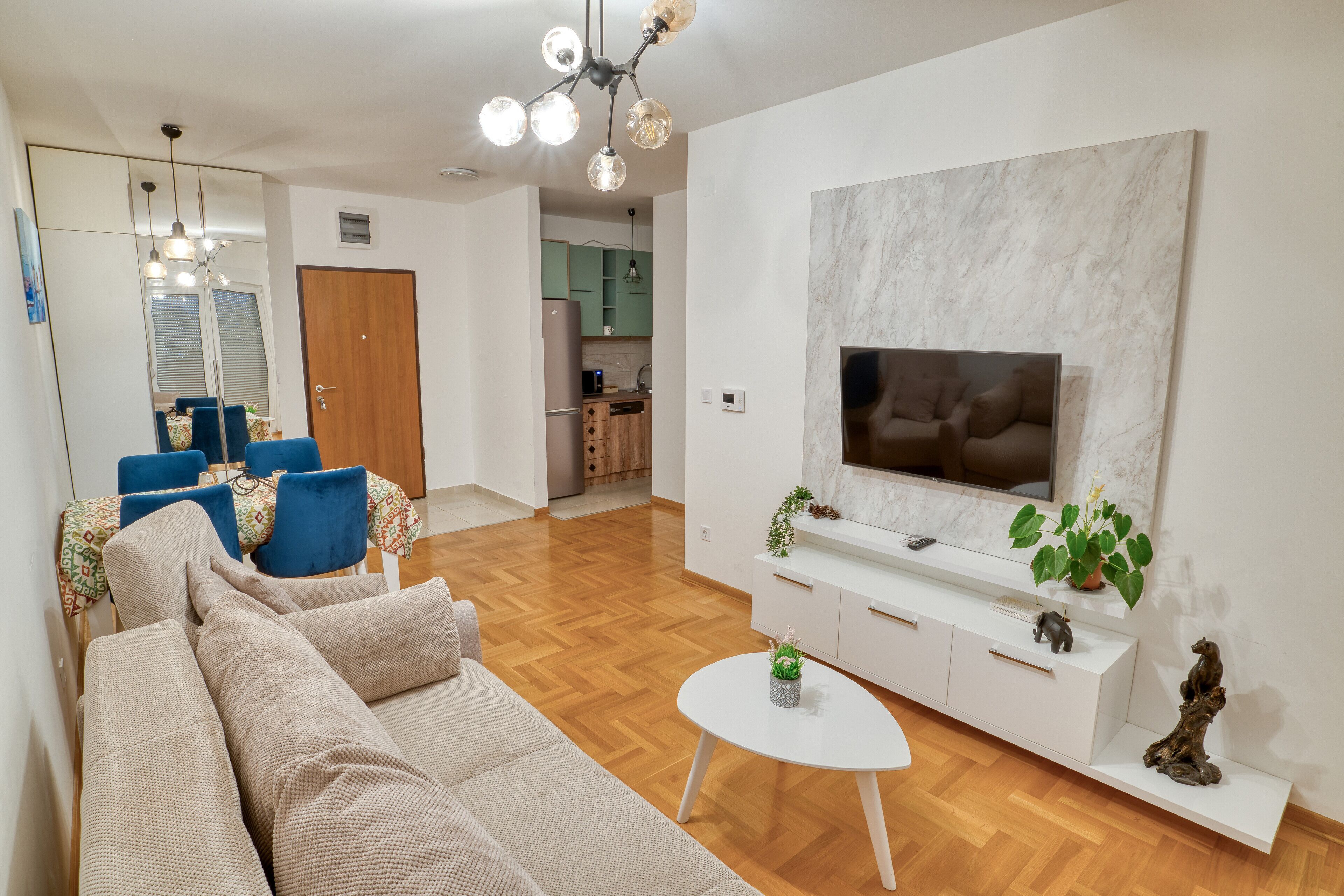 Een moderne woonkamer met een bank, een salontafel en een aan de muur bevestigde televisie.