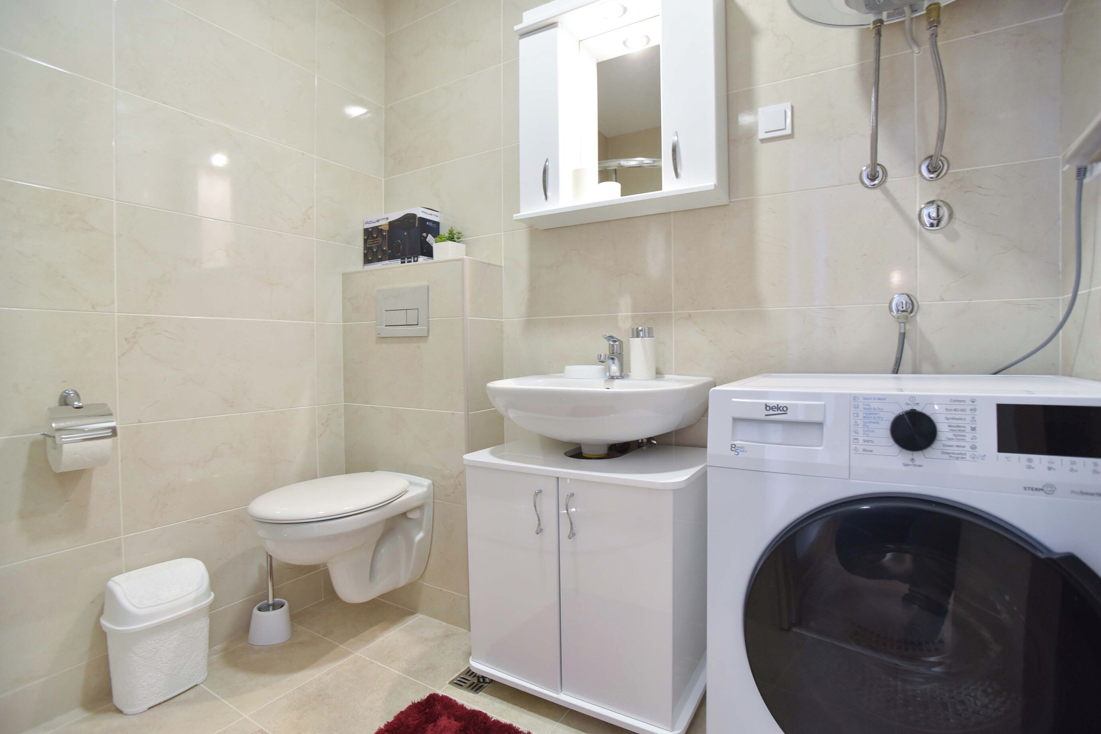 Un baño moderno con inodoro, lavamanos y lavadora.