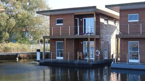 Une péniche en bois dotée d’un balcon, d’une petite terrasse et d’une fenêtre.