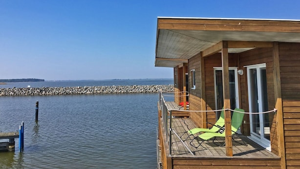 Une cabane en bois dotée d’un balcon donnant sur une étendue d’eau paisible.