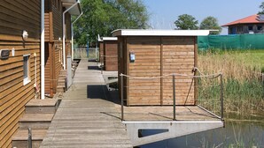 Un bâtiment en bois avec une jetée qui s’avance sur une étendue d’eau, reliée au bâtiment par une passerelle en bois.