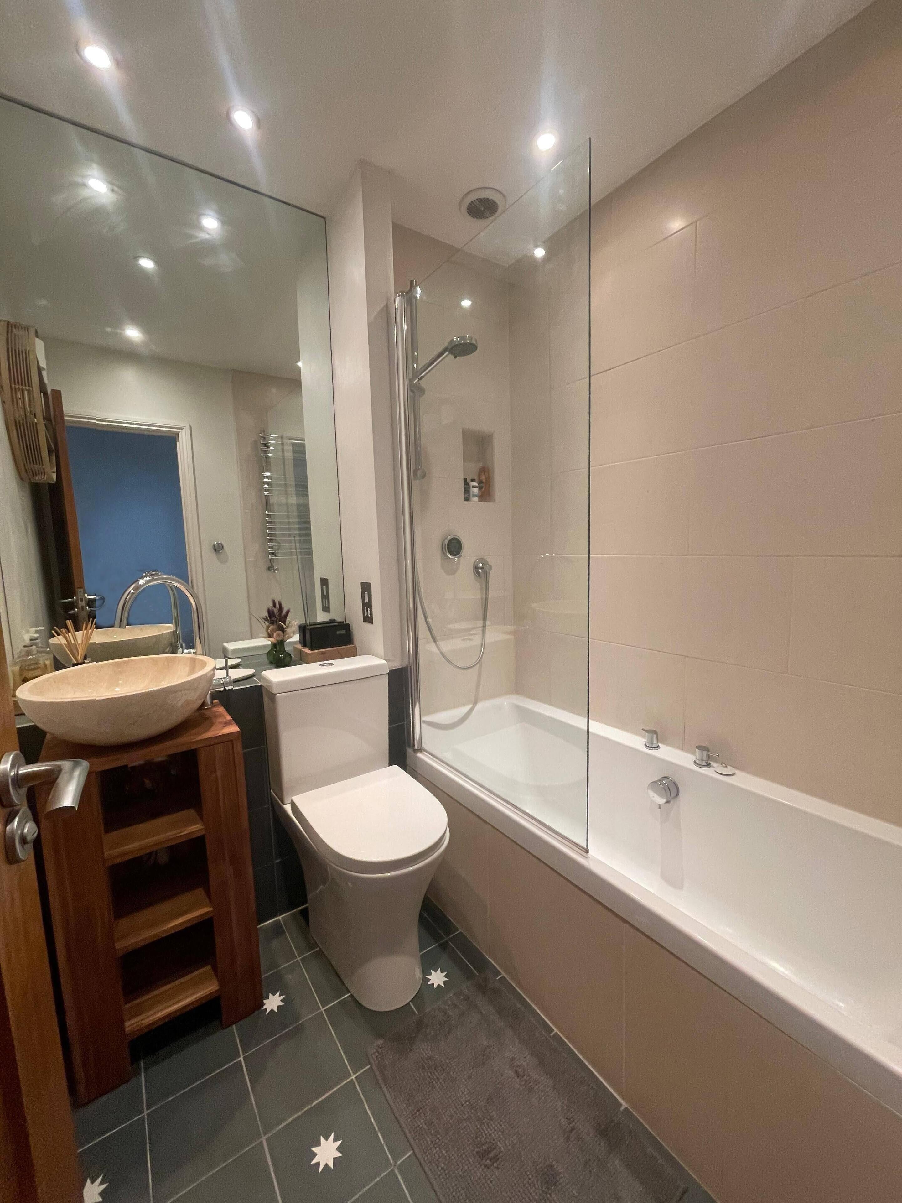 Un baño moderno con una bañera grande, un inodoro separado y un tocador con lavabo.