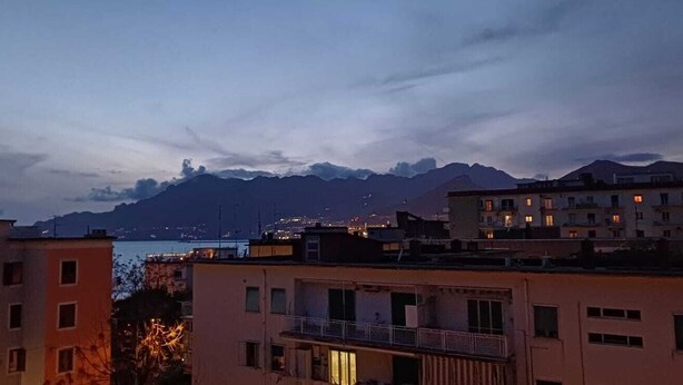 Paisatge urbà a la capvespre amb edificis i muntanyes al fons.