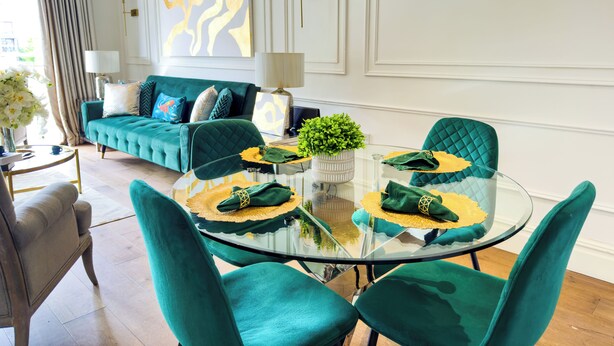 A modern living room with a teal sofa, a glass coffee table, and matching teal chairs.