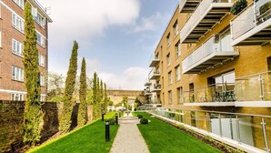A pathway flanked by buildings with balconies and a brick wall.