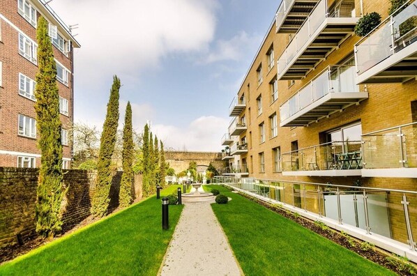 Un chemin bordé de bâtiments dotés de balcons et d’un mur en briques.