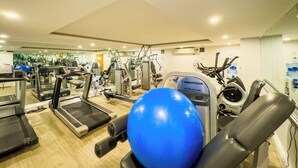 A gym with treadmills, elliptical machines, and a blue exercise ball.