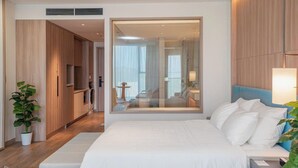 Quarto de hotel moderno com uma cama grande, um closet espaçoso, uma cozinha compacta e um espelho grande que reflete o ambiente.