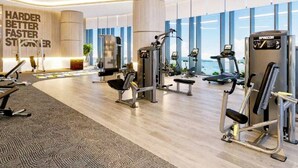 Uma academia moderna com diversos equipamentos de exercício, janelas amplas e frases motivacionais nas paredes.