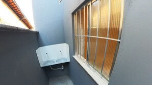 Un couloir étroit, avec une fenêtre sur la droite et un appareil de climatisation blanc fixé au mur.