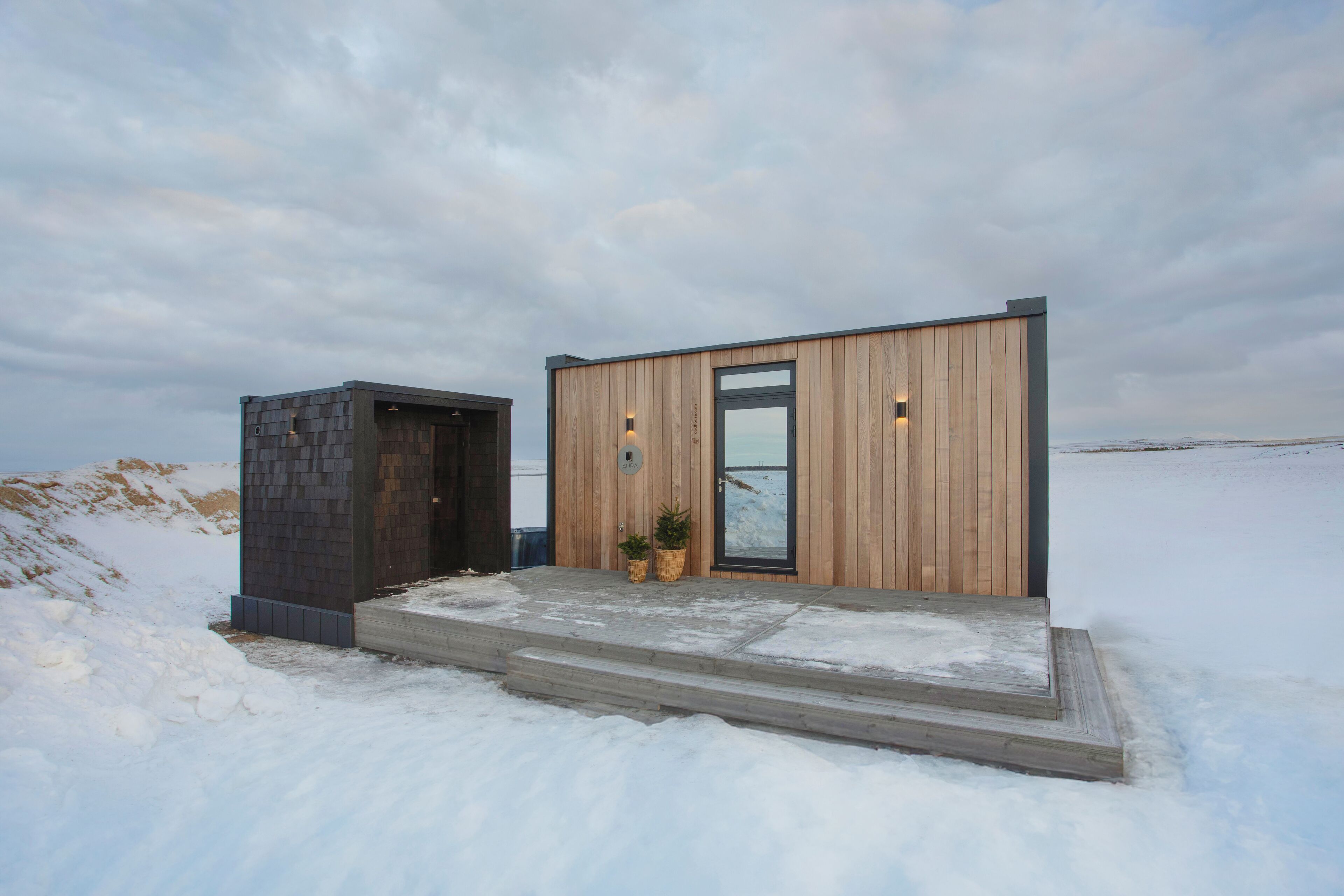 Un bâtiment moderne, doté d’une façade en bois et d’une porte en verre, situé dans un paysage enneigé.