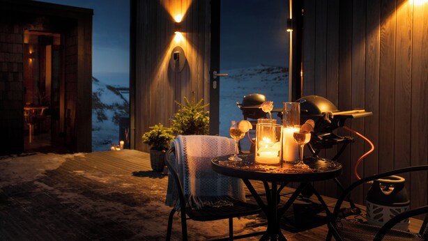 Un espace extérieur accueillant, aménagé avec une table pour deux, agrémenté de bougies, de verres et d’un barbecue.