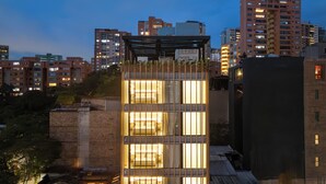 A modern hotel with a unique facade featuring vertical wooden slats and illuminated rooms. - LIN Boutique Hotel by HOUSY HOST (Medellín)