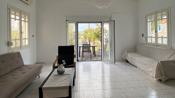 A spacious living room with a sofa, a coffee table, and a view through a glass door to an outdoor patio.