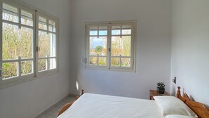 A bedroom with a wooden bed, two windows, and a ceiling light.