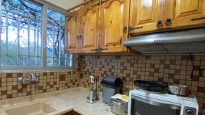 A kitchen with wooden cabinets, a window, a microwave, and a coffee maker.